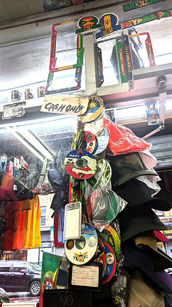 Nostrand store interior. Hand-written "Cash Only" is displayed among a variety of Caribbean CDs and banners, which are hung from the ceiling.